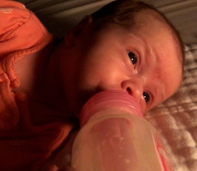 Baby lying down drinking bottle