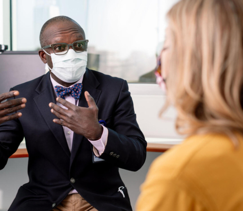 Masked doctor speaking with patient