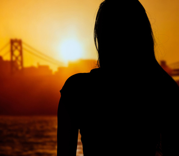 Woman looking at bridge in sunset