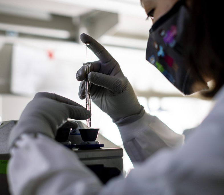 Doctor using syringe on sample in lab