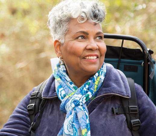 Woman walking through woods with backpack