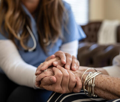 Medical professional holding a patient's hands in comfort