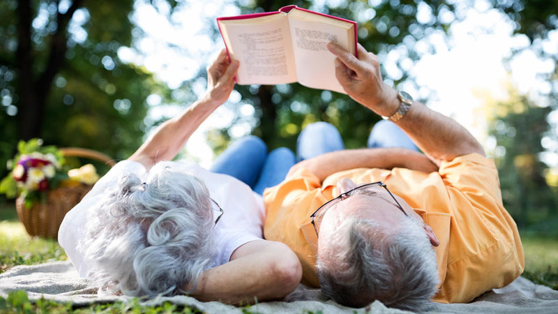 Senior couple reading a book outside