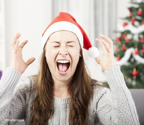 Woman wearing Santa hat appearing stressed out.