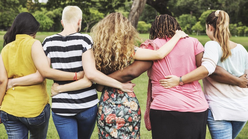 Five women walking with arms around each other's waist