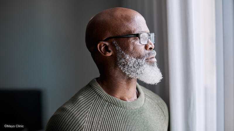 Man with beard looking out window