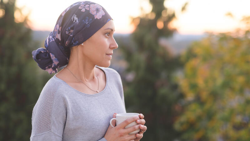 Woman with head scarf drinking coffee outside