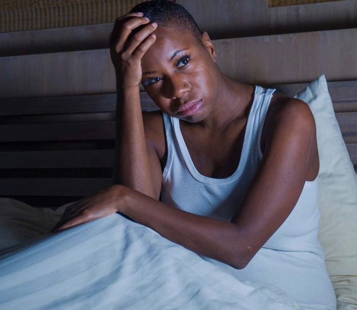 Person sitting in bed with head in hand