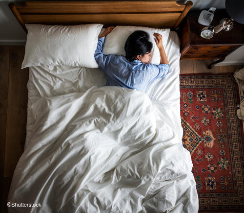 Adult laying down in bed.