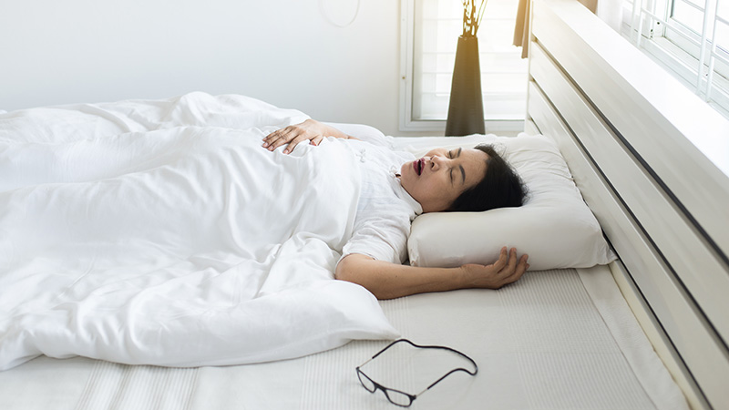 Woman sleeping on her back in bed