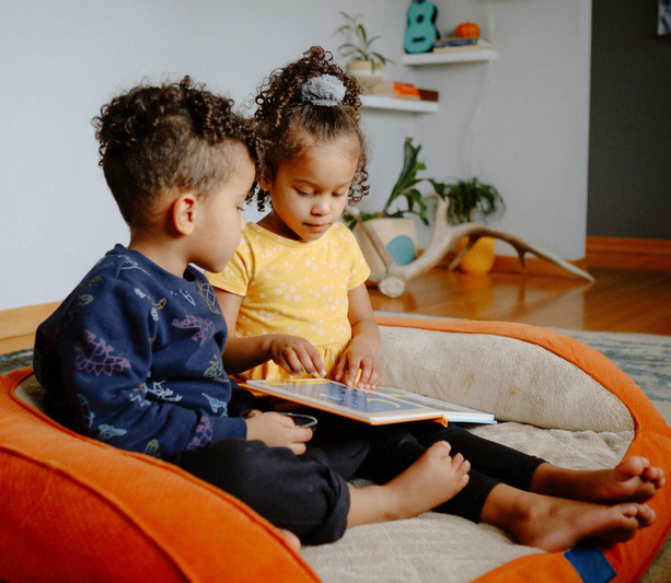 Two children sitting together and reading a book