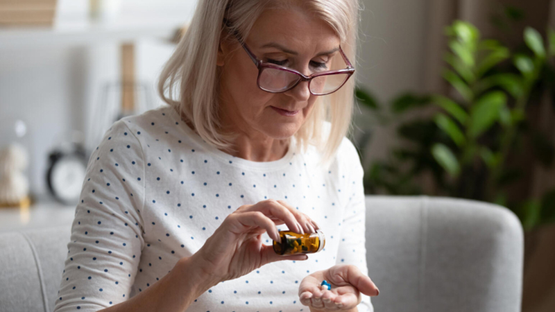 Older woman getting pills out of bottle