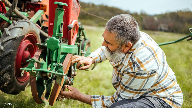 Man fixing piece of farm equipment