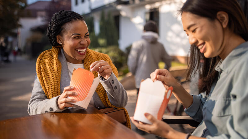 Two women eating takeout outside