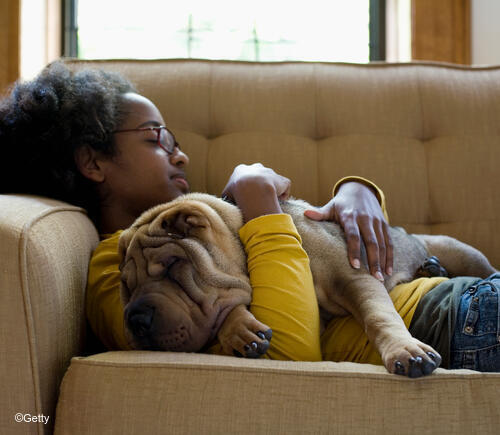 Girl cuddling with dog on couch