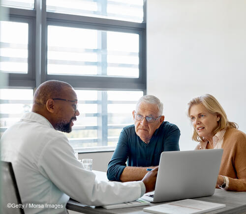 A Black male physician speaking with an older man and woman