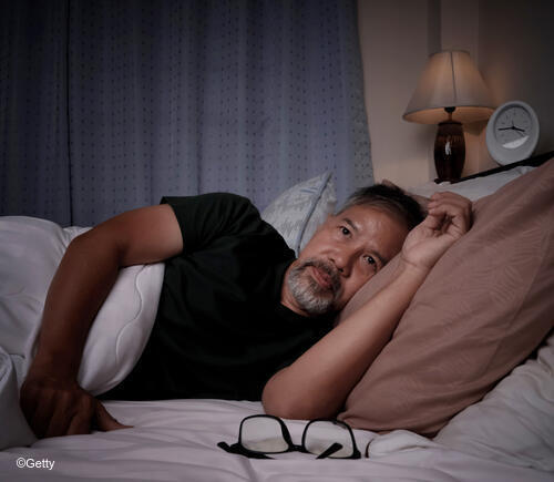 Man in bed struggling to fall asleep