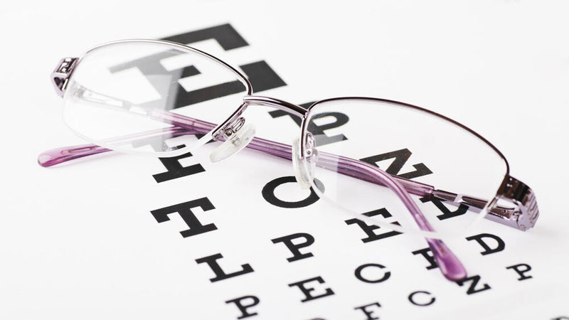 Pair of eye glasses laying on a vision chart