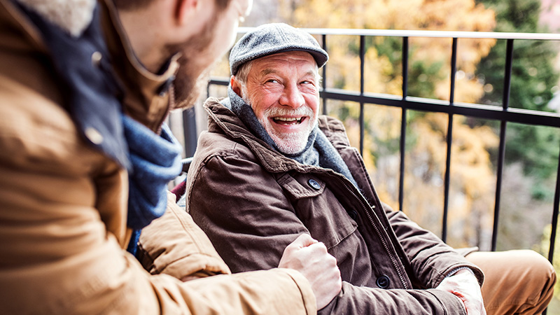 Two men sitting on a bench laughing