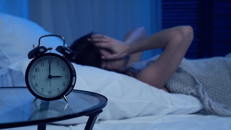 Woman in bed with a clock on night stand