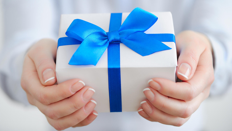 Woman holding white gift box with blue ribbon