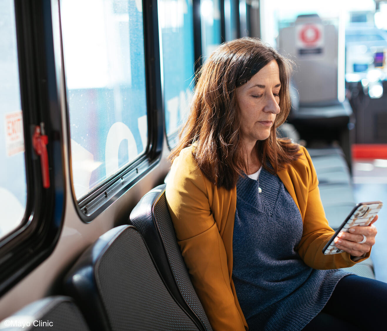 Middle aged woman using cell phone on a city bus