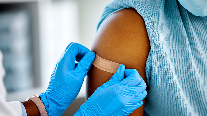 Bandaid being applied on shoulder after a vaccination