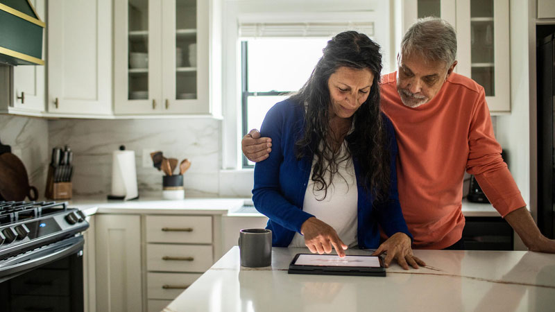  Couple using digital tablet in kitchen