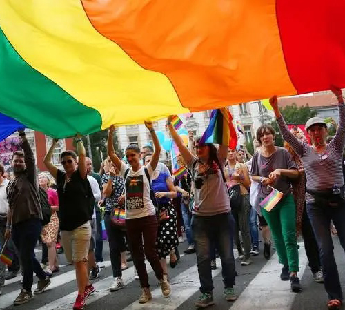 Group walking under rainbow flag at Pride Parade