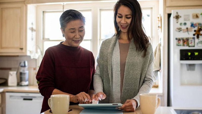 Older mother and daughter using the e-tablet