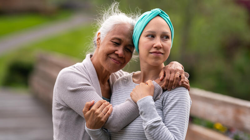 Older mother hugging her daughter with a headscarf on