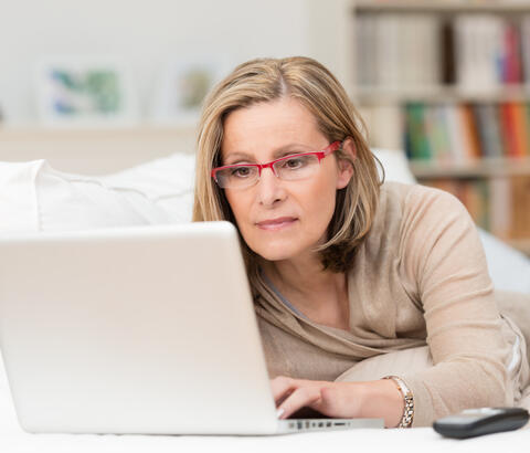 Woman working on laptop on her bed