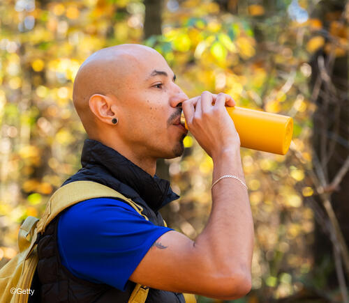 Man drinking from yellow water bottle.