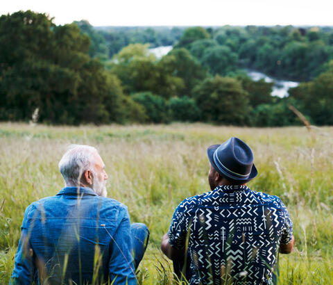 Two men sitting in a meadow