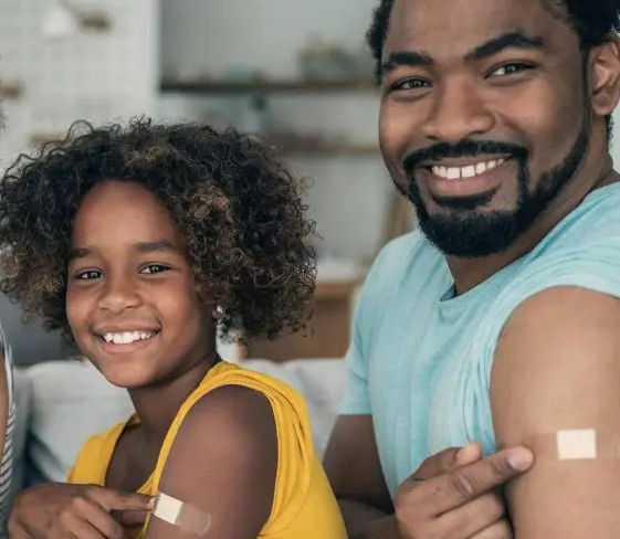 Father and daughter smiling with bandaids