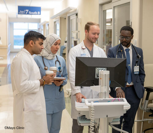 Four healthcare professionals in hospital hallway.