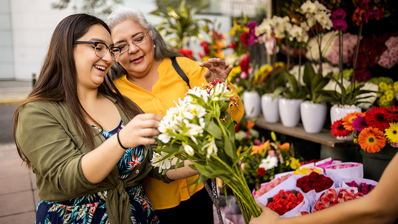 Two women shopping flowers at an outdoor market