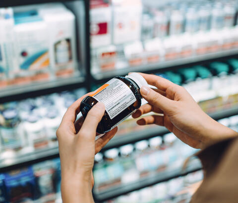 Person reading label on pill bottle