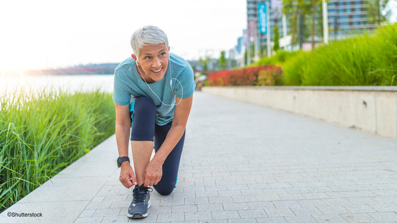 Older woman tying her shoe during a walk.