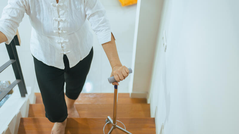 Woman using a cane to walk up stairs