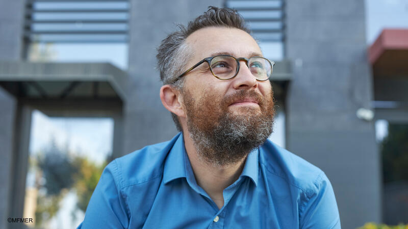 Man with glasses and beard looking off camera