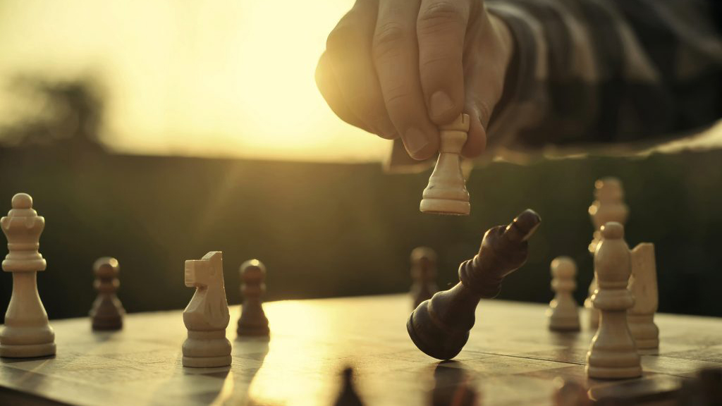 Person knocking over chess piece on board