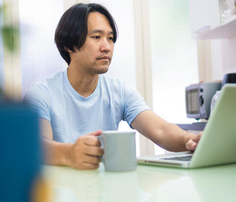 Man drinking coffee and using laptop