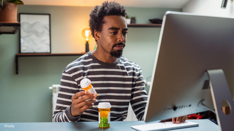 Man on computer looking at pill bottles