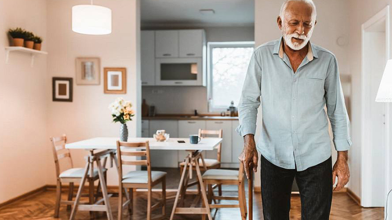 Old man with cane walking in his kitchen