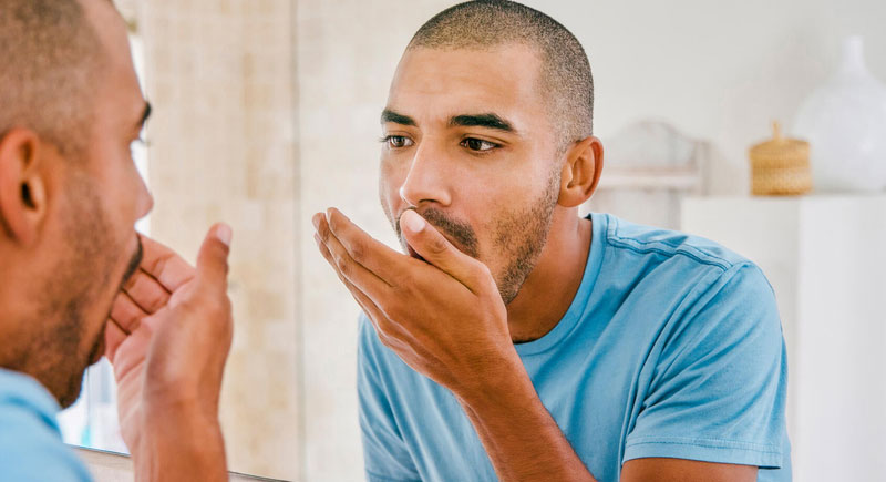Man checking his breath in the mirror