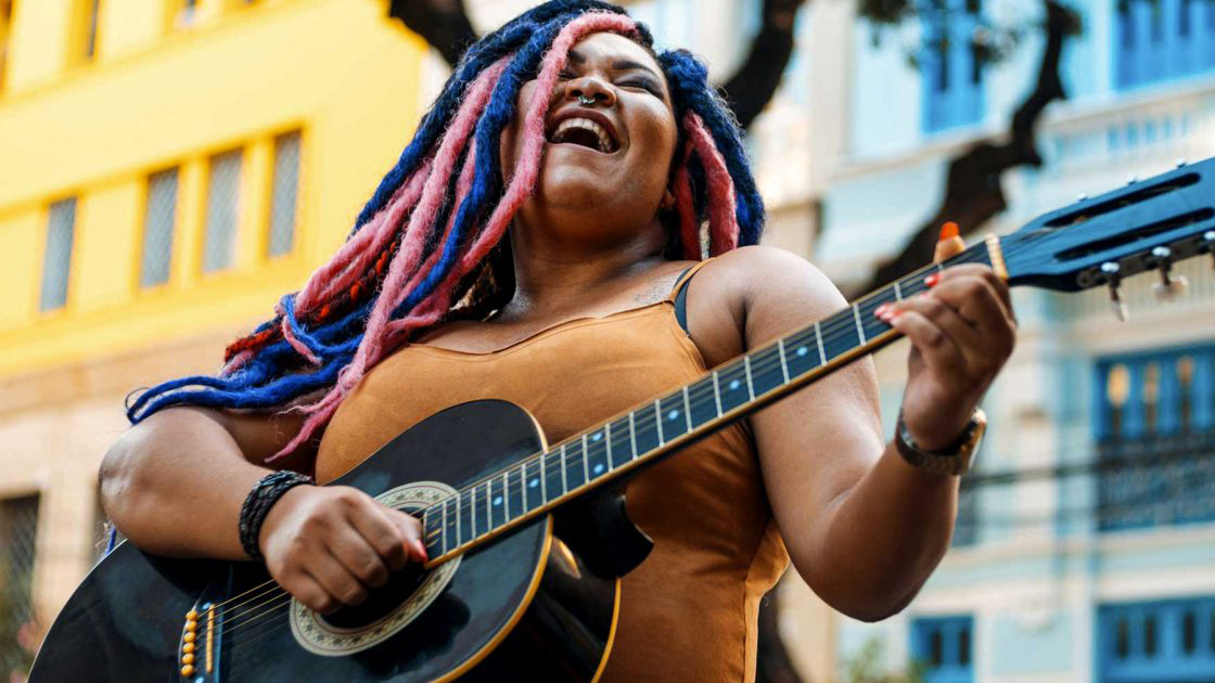 Person singing and playing guitar outside