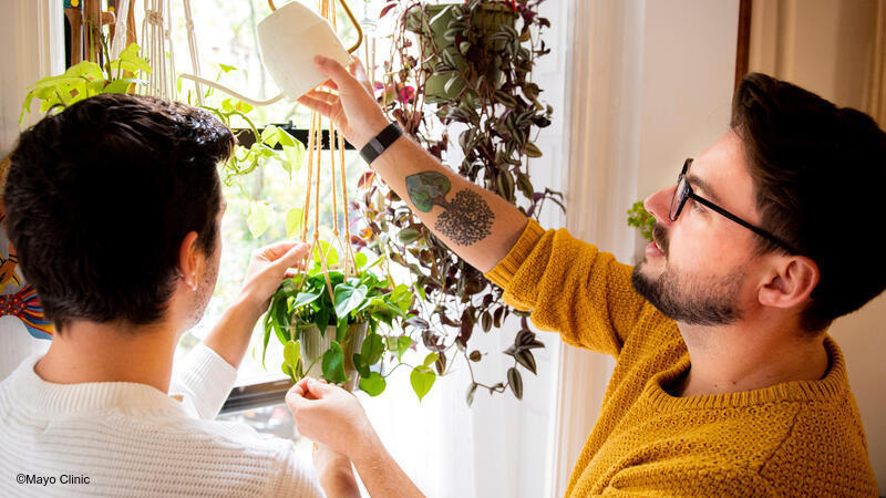 Adult men watering house plants.