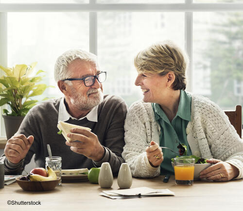 Older couple sitting down and eating breakfast