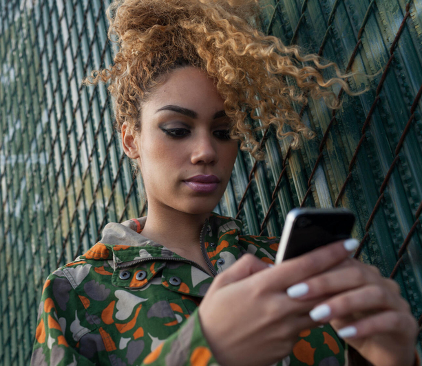 Woman in front of fence looking at phone